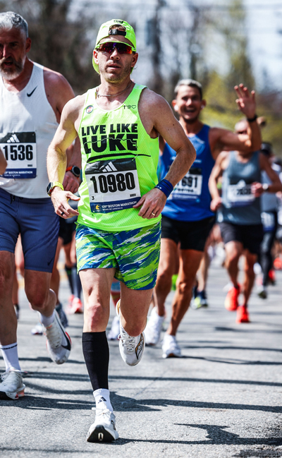Man wearing green athletic-wear that reads "Live Like Luke" running in marathon